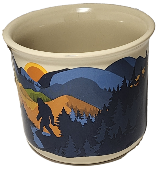 A large cup with a picture of trees and mountains.