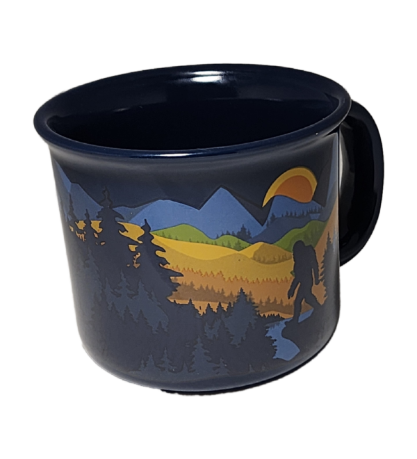 A black mug with trees and mountains on it.