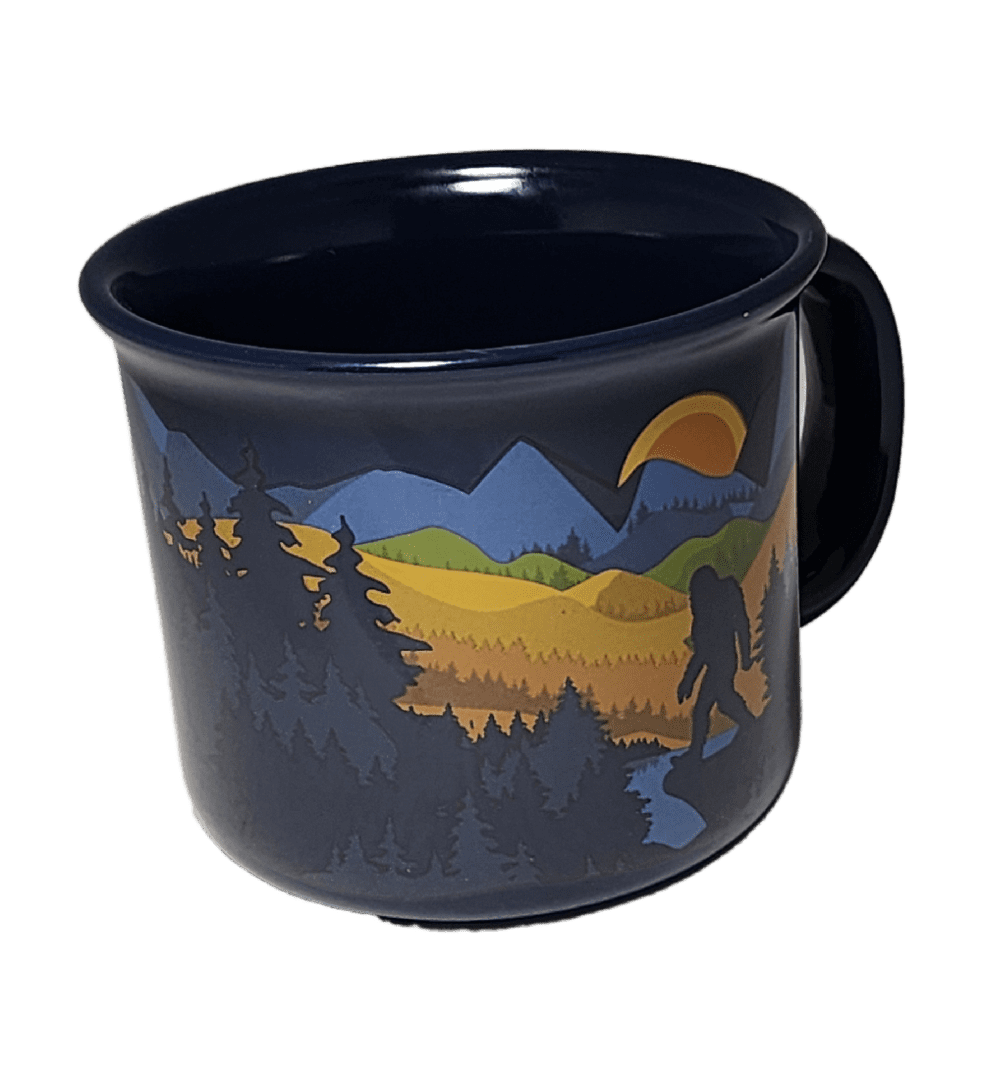 A black mug with trees and mountains on it.