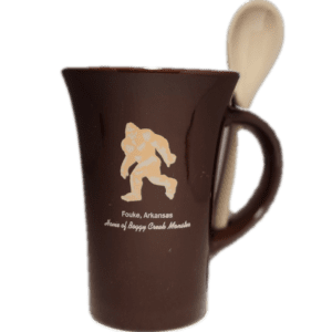 A brown coffee mug with a wooden spoon inside of it.