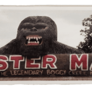 A large gorilla statue sitting in front of a monster mall sign.