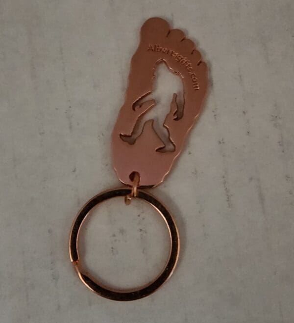 A metal keychain with a foot print on it.